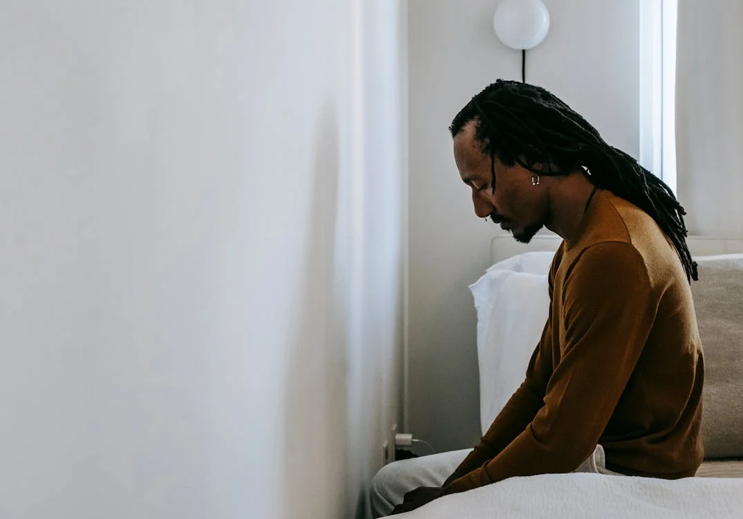 Depressed black man on bed at home