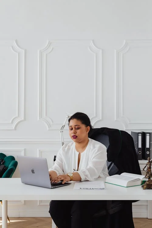 A Woman Sitting at the Office Desk Using a Laptop