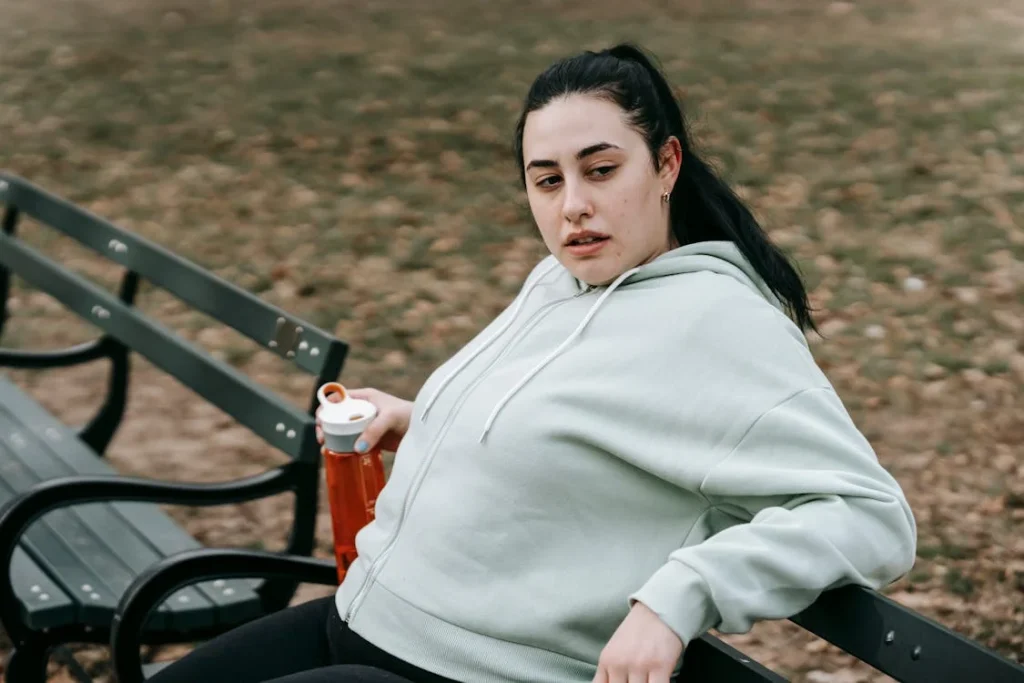 Calm young woman resting on bench after training in park